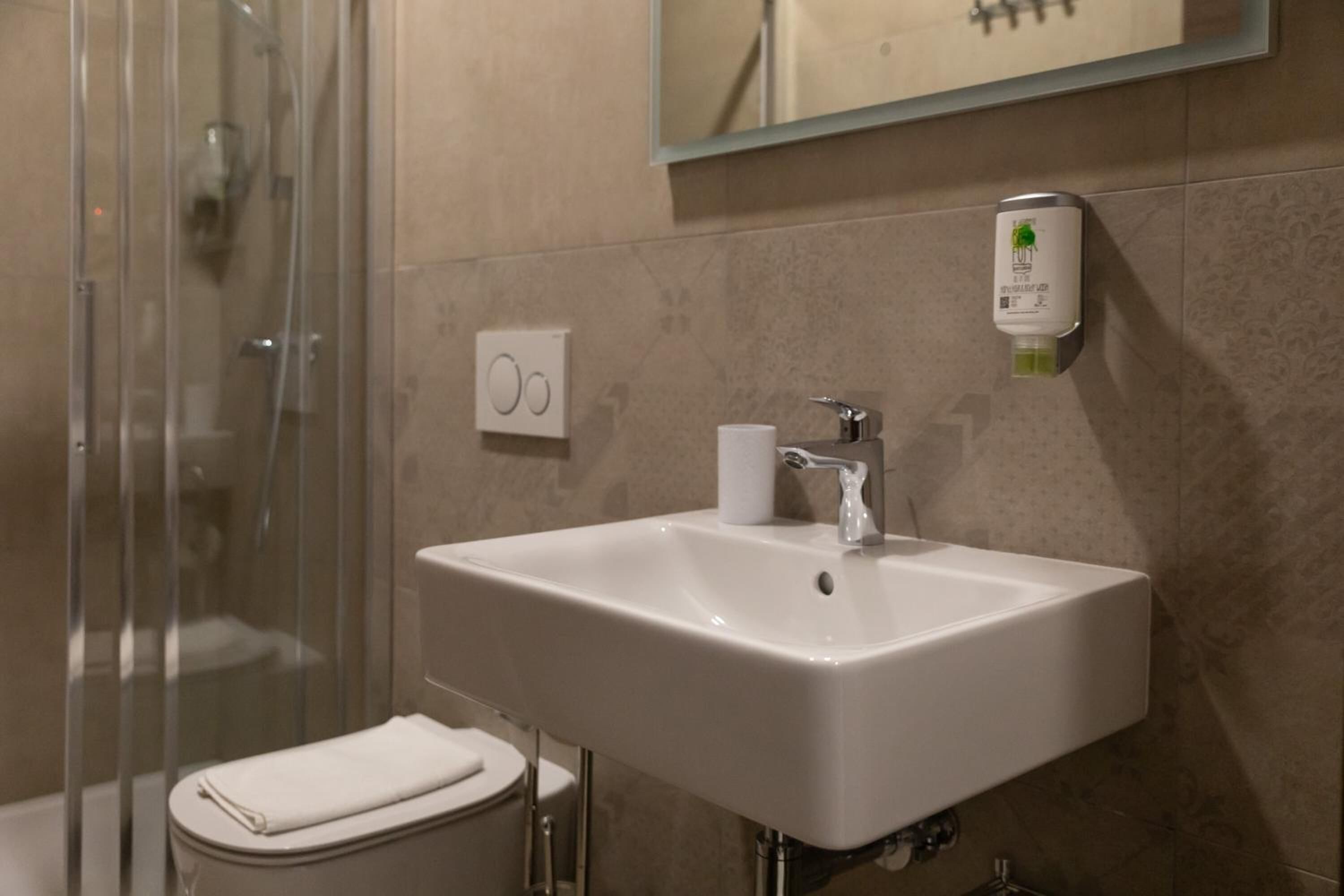 Une salle de bain avec un lavabo blanc, une cabine de douche en verre et des toilettes.