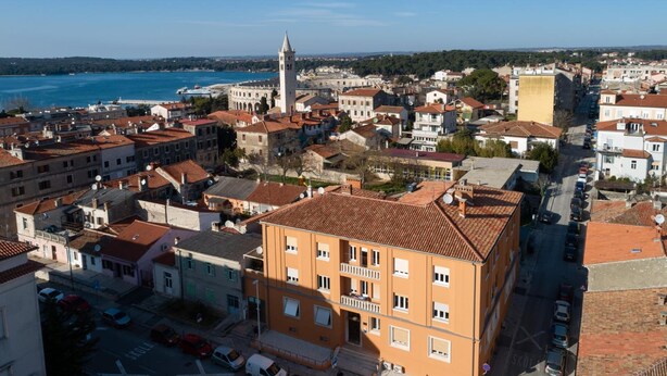 Un pueblo costero con edificios históricos, una torre destacada y una vista despejada del mar.