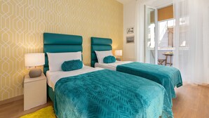 A hotel room with two beds, a nightstand with a lamp, a yellow rug, and a geometric patterned wall. - Preziosa (Pula)