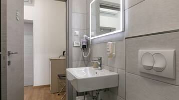 Une salle de bain moderne avec un lavabo blanc, une douchette à main et un porte-serviettes.