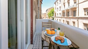 Un balcón con una mesa dispuesta para el desayuno, con cruasanes, naranjas y jugo.