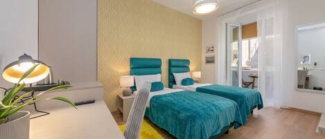 Ett modernt hotellrum med två sängar, ett skrivbord, en krukväxt och en ljusgul matta.