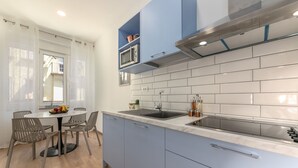 A modern kitchen with blue cabinets, a white tiled backsplash, and a built-in microwave. - Preziosa (Pula)
