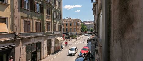 Una calle estrecha flanqueada por edificios, con un paso de peatones y coches estacionados.
