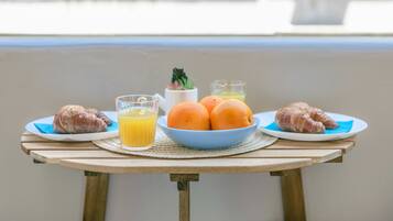 Desayuno con cruasanes, naranjas y zumo de naranja sobre una mesa de madera.