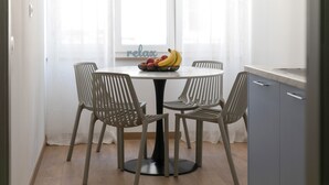 A dining area with a round table, four chairs, and a bowl of fruit. - Preziosa (Pula)