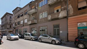 Calle con coches aparcados y un edificio con un cartel que dice 'BIG BRANDS LOW PRICES'.