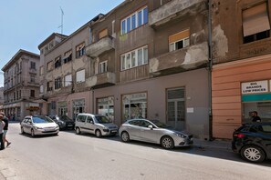 A street with parked cars and a building with a sign for 'BIG BRANDS LOW PRICES'. - Preziosa (Pula)