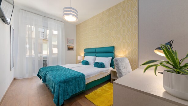 Un dormitorio moderno con una cama, mesitas de noche, un escritorio y una planta en maceta.