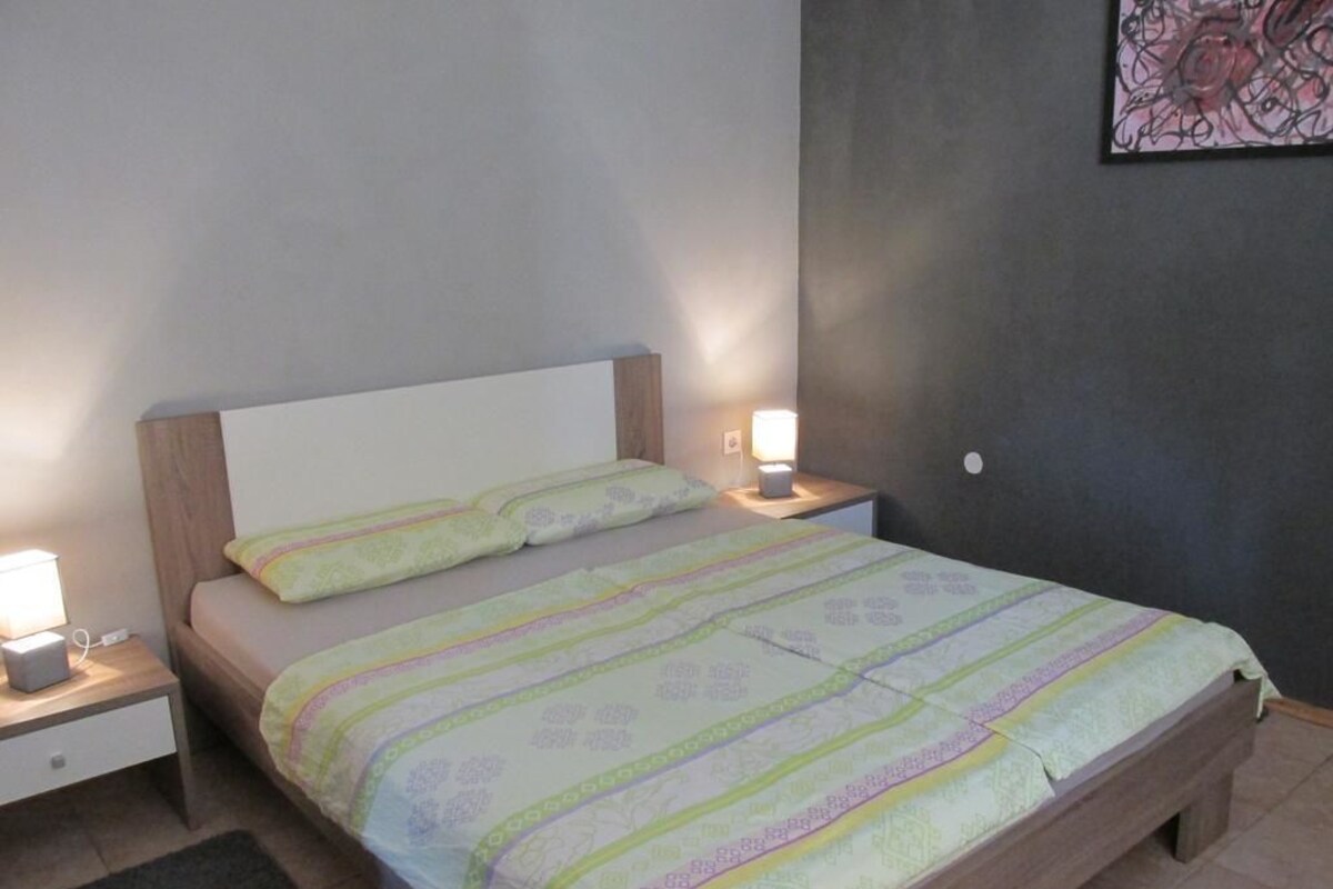 Ein Schlafzimmer mit einem Bett, zwei Nachttischen und einer Wandlampe.
