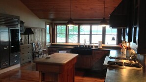 A kitchen with wooden cabinets, a central island, stainless steel appliances, and pendant lighting.