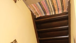 Un escalier avec une rampe en bois et un tissu rayé et coloré au sommet.