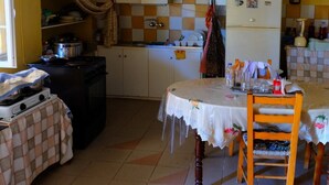 Une cuisine de taille réduite avec des meubles blancs, un réfrigérateur et une table à manger avec des chaises.