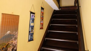 Un escalier en bois, avec un mur à texture et une affiche représentant un cerisier en fleurs.