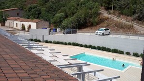 A rooftop swimming pool with a view of a hillside and a road with cars. - THREE-ROOM APARTMENT WITH SOLARIUM AND POOL (Viddalba)