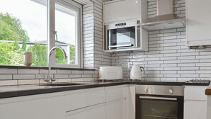 Eine moderne Küche mit weißen Schränken, einem Edelstahlbackofen, einer Mikrowelle und einem Toaster.
