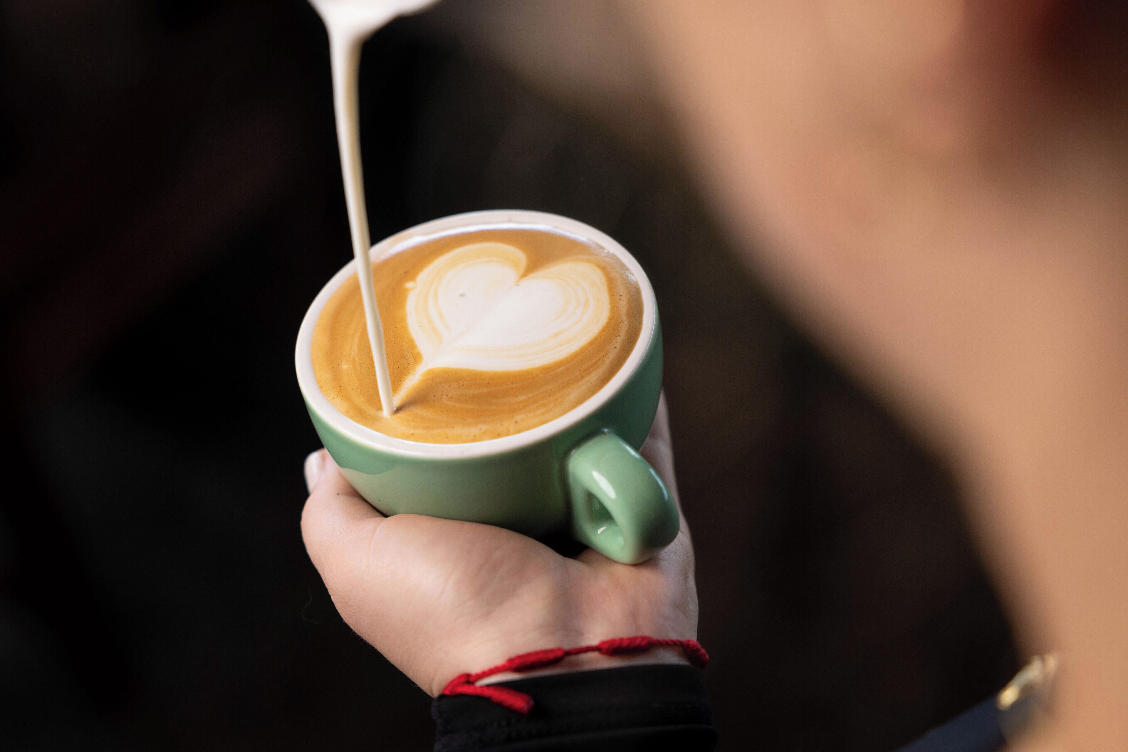 Una persona sosteniendo una taza de café con un diseño de corazón en la espuma.