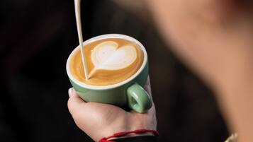 Una persona sosteniendo una taza de café con un diseño de corazón en la espuma.