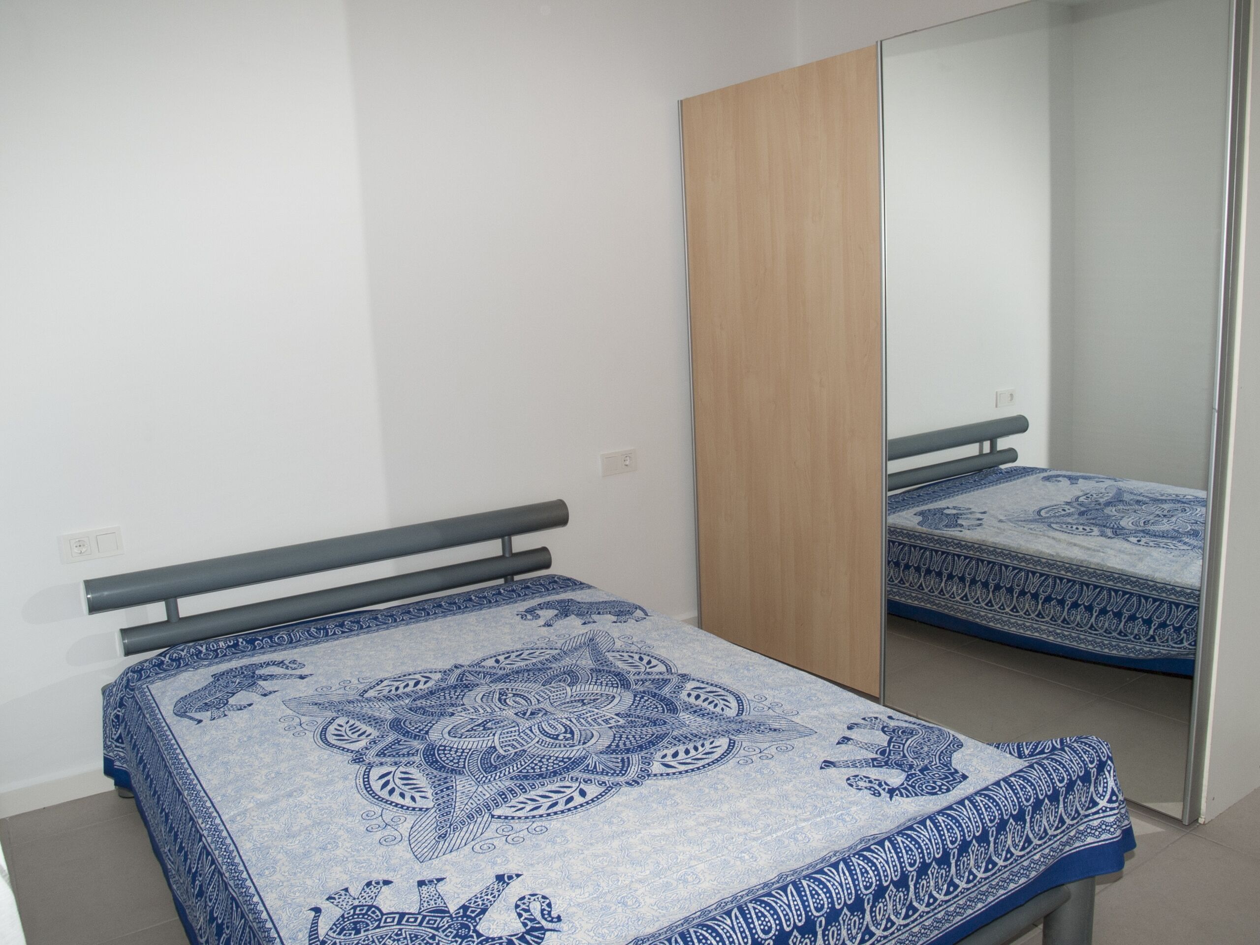 Une chambre à coucher avec un lit, une armoire en bois et un miroir.