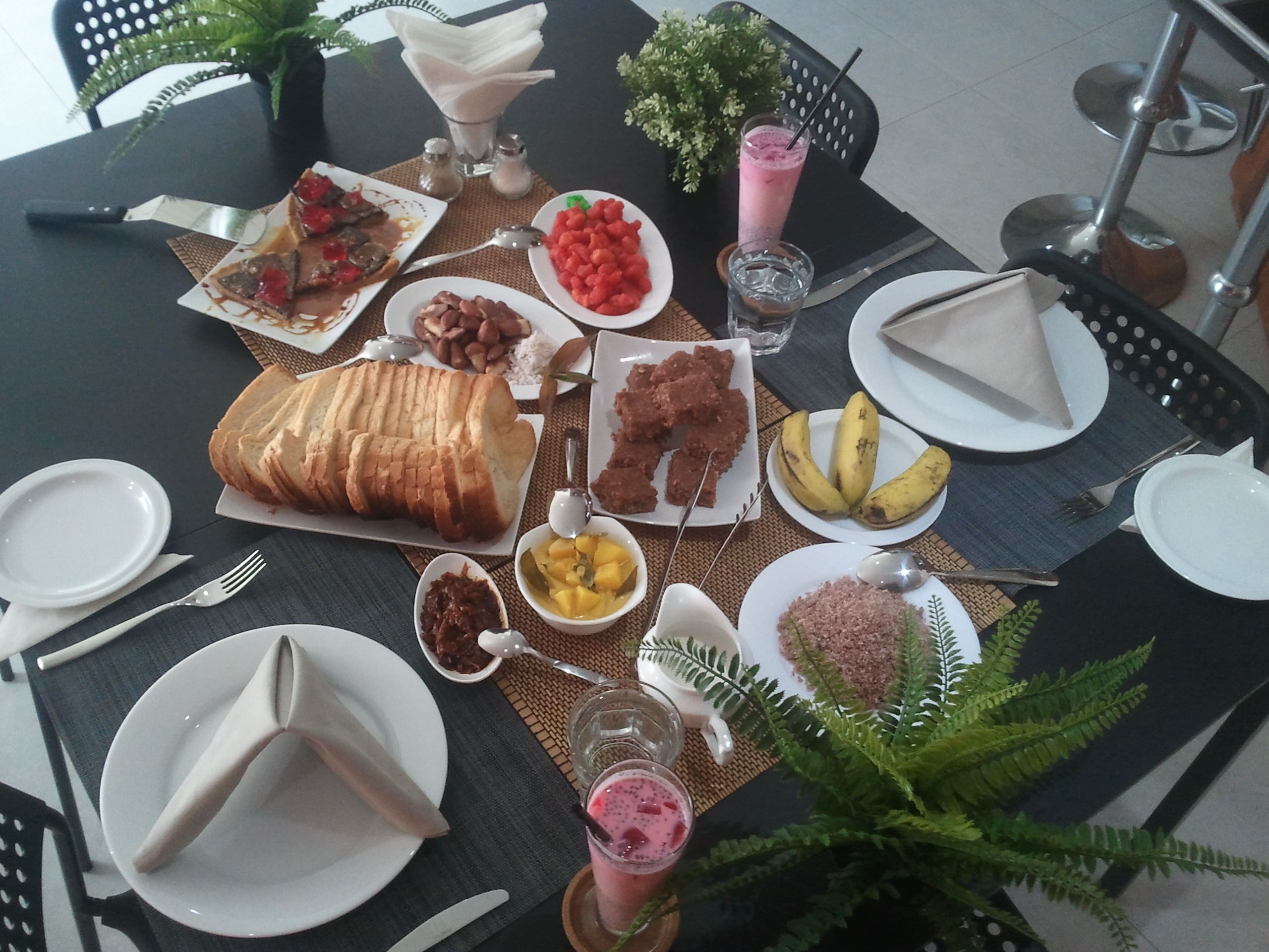 Une table dressée avec différents plats, notamment du pain, des fruits et une boisson.