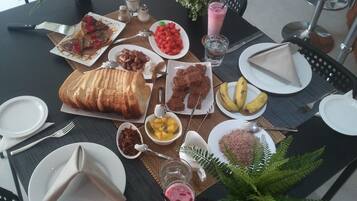 Une table dressée avec différents plats, notamment du pain, des fruits et une boisson.