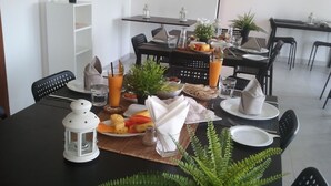Una mesa de comedor dispuesta con platos, cubiertos, una bebida y una planta de helecho.