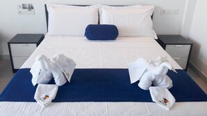 Una habitación de hotel con una cama grande, dos mesitas de noche y un cojín azul decorativo.