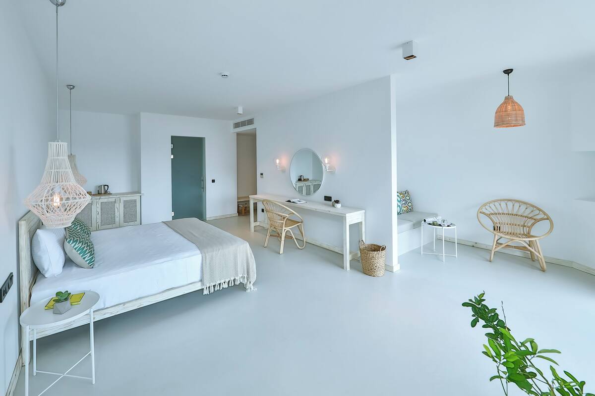 Un dormitorio moderno y minimalista con cama, escritorio y dos sillas.
