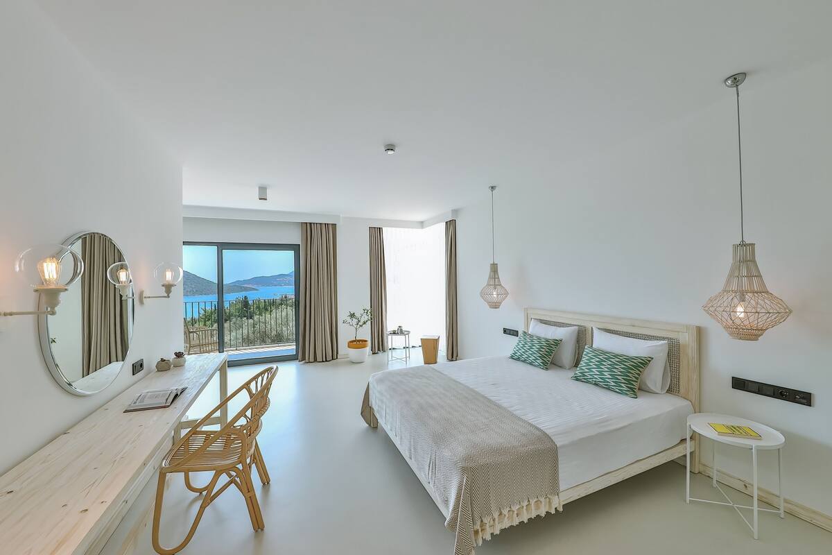 Un dormitorio moderno con una cama grande, un escritorio y una silla. Hay un ventanal con vistas al exterior.