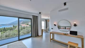 Una habitación de hotel moderna con un balcón grande, un escritorio de madera, una computadora portátil y un espejo redondo.