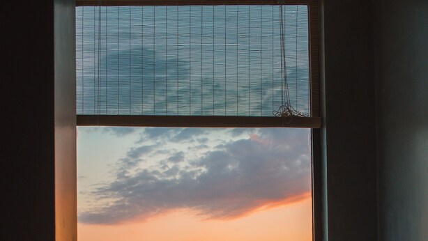 A room with a large window overlooking a sunset over a body of water and mountains. - Carruba Boutique Hotel (Kas)