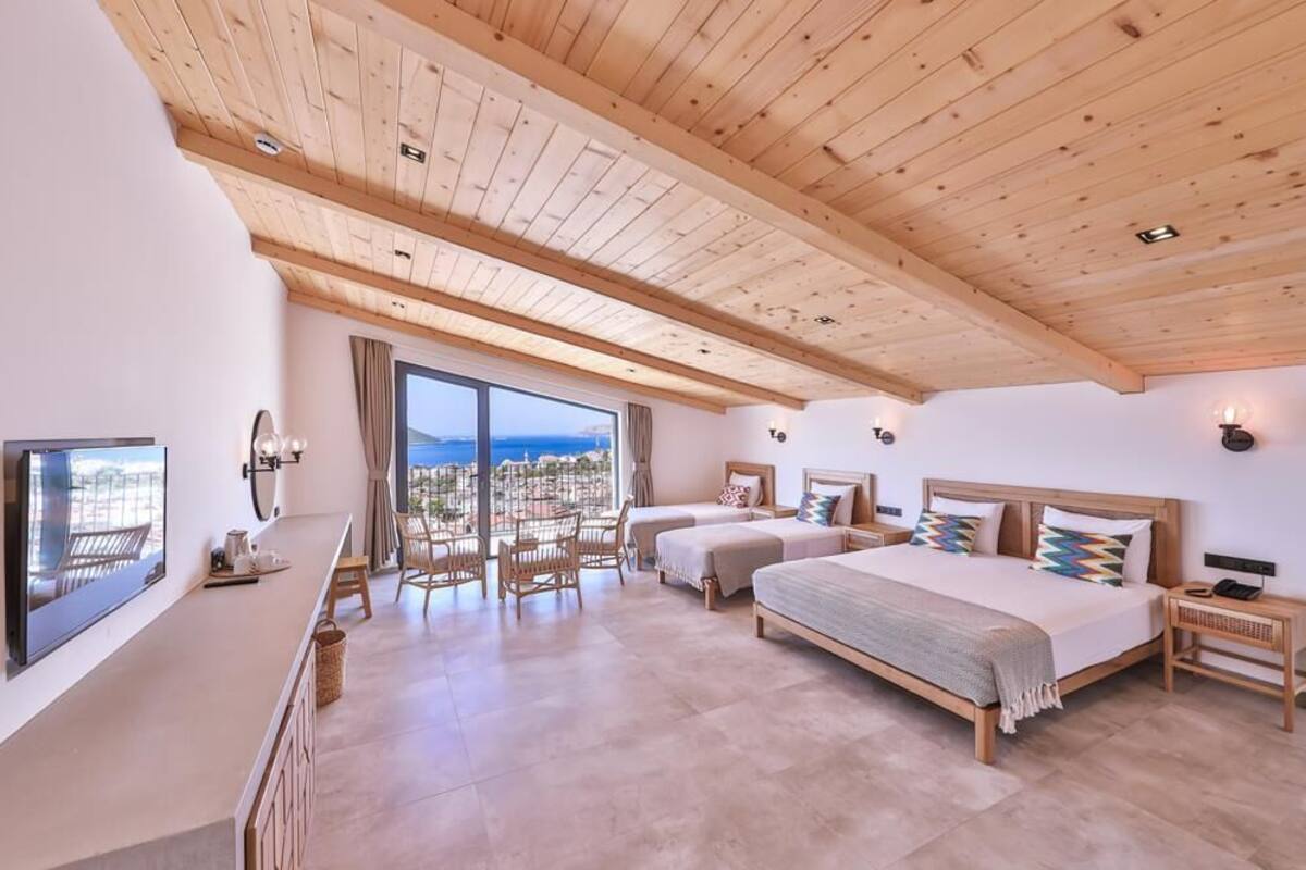 Un dormitorio espacioso con dos camas, televisión y balcón con vistas.
