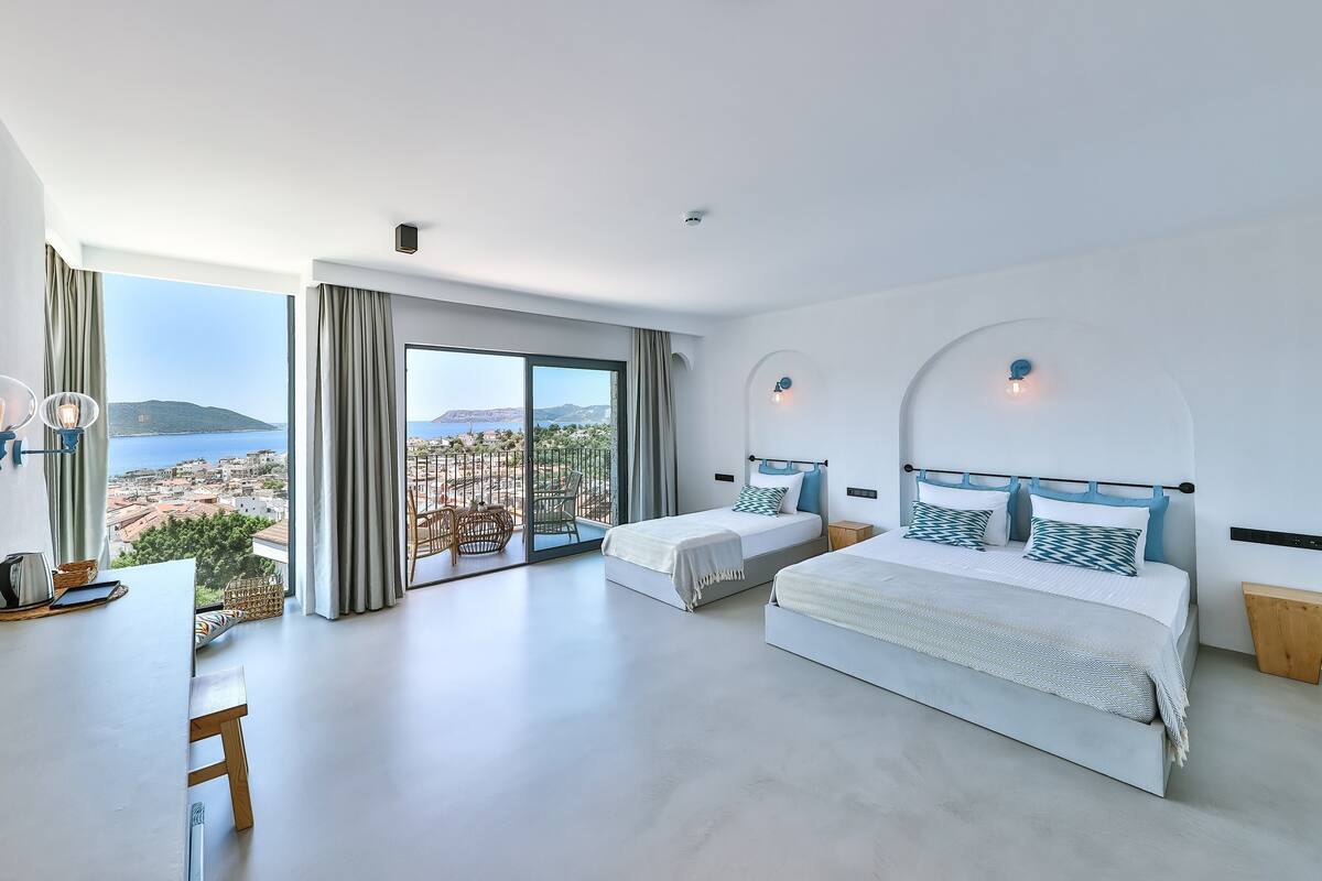 Un dormitorio moderno con una cama grande, una cama más pequeña y un balcón con vistas al mar.