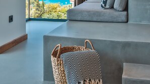 A modern living room with a large window offering a scenic view of a coastline. - Carruba Boutique Hotel (Kas)