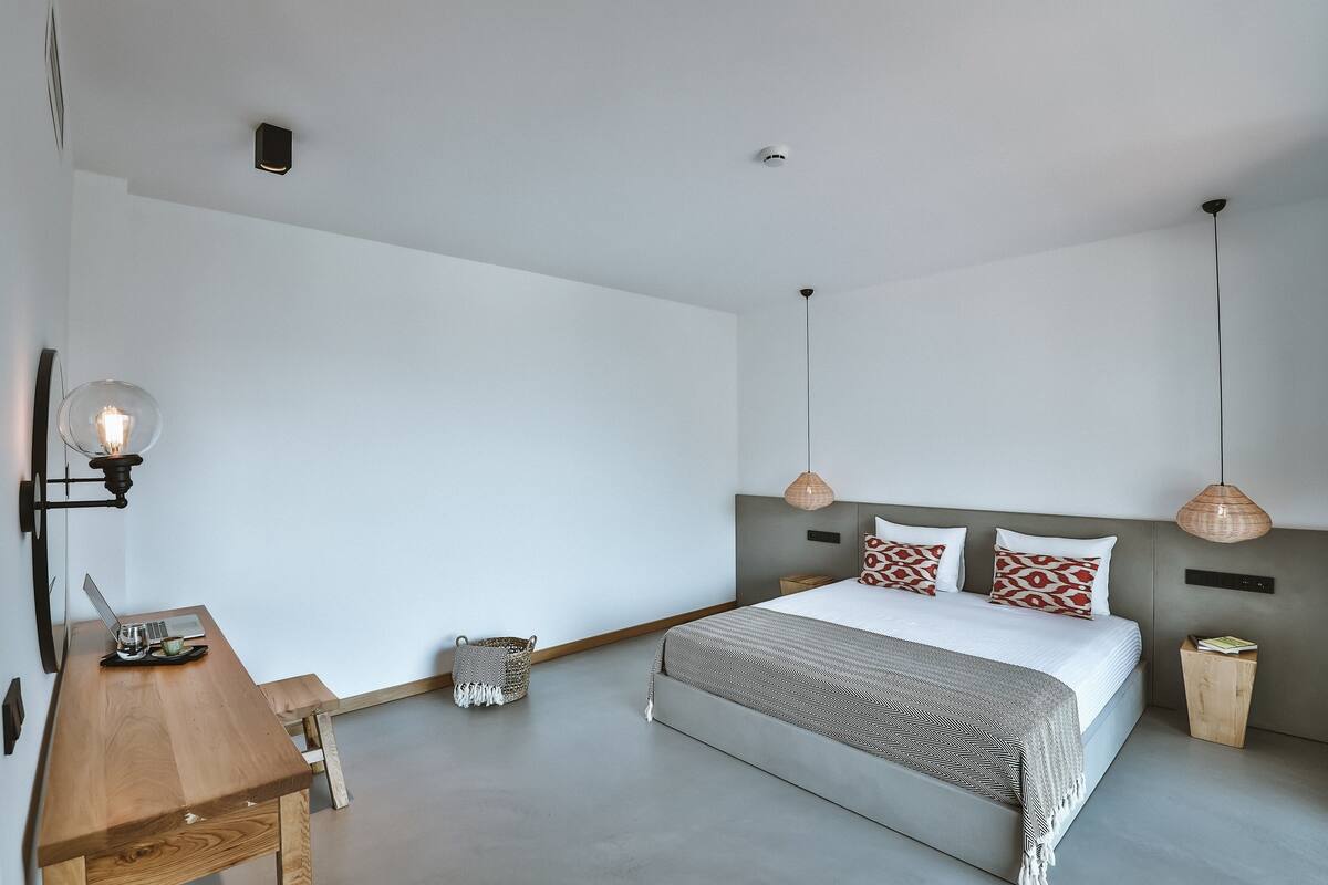 Un dormitorio moderno con una cama grande, un escritorio de madera y una lámpara colgante.