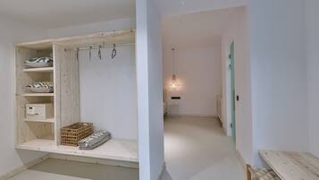 A room with a wooden wardrobe, a small table, and a hanging light fixture.