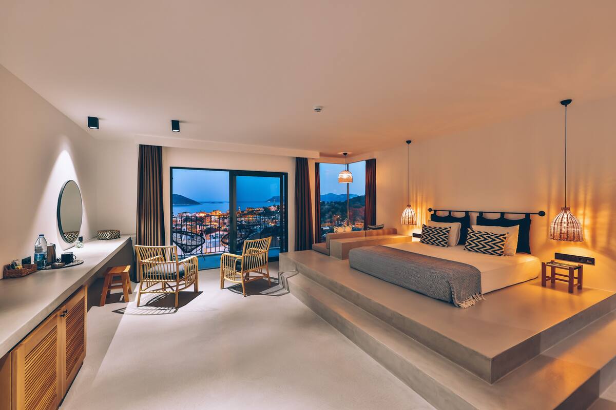 Una habitación de hotel moderna con una cama grande, zona de estar y vistas a la ciudad.