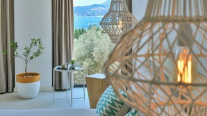 A modern room with large windows, wicker pendant lights, a potted plant, and a view of the sea. - Carruba Boutique Hotel (Kas)