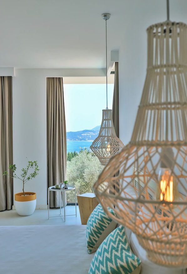 A modern room with large windows, wicker pendant lights, a potted plant, and a view of the sea. - Carruba Boutique Hotel (Kas)