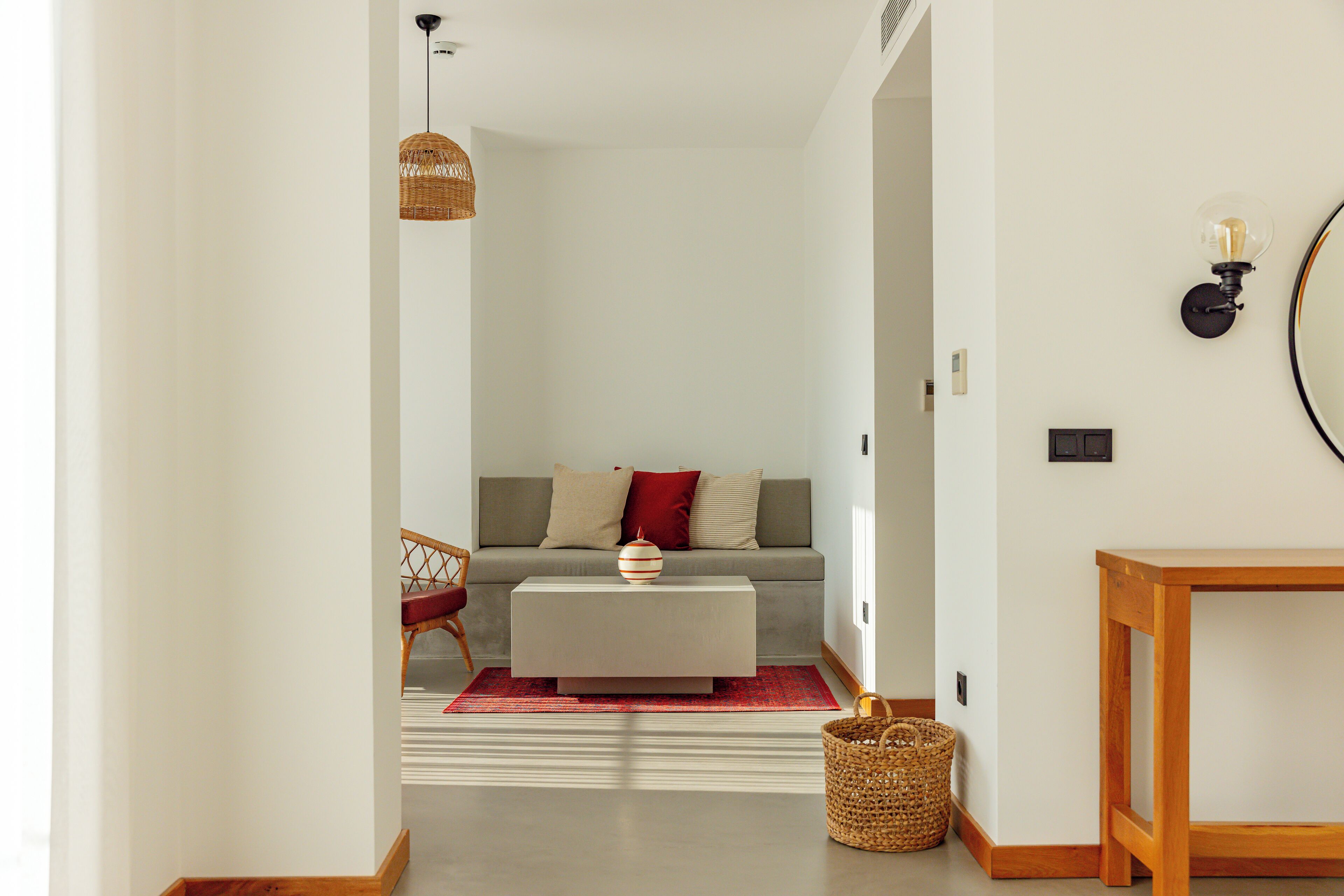 A modern living room with a sofa, a coffee table, a wicker basket, and a wooden side table.