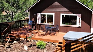 Una cabaña con terraza, asientos al aire libre y una parrilla.