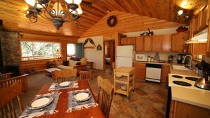 Un acogedor interior de cabaña de madera con comedor, cocina y sala de estar.