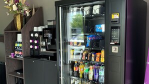 Máquina expendedora con diversas bebidas y aperitivos, un terminal de pago y una pequeña pantalla.