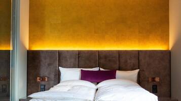 A modern bedroom with a large bed, a headboard with integrated lighting, and a minimalist design.
