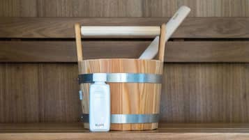 Un seau en bois, une bouteille blanche et une cuillère en bois, posés sur une étagère en bois.