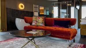 Una sala de estar moderna con un sofá rojo, una mesa de centro de vidrio y una alfombra colorida.