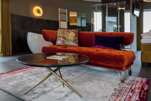 Una sala de estar moderna con un sofá rojo, una mesa de centro de vidrio y una alfombra colorida.