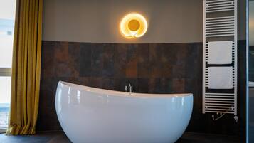 A modern bathroom with a freestanding bathtub, a wall-mounted towel rack, and a circular light fixture.