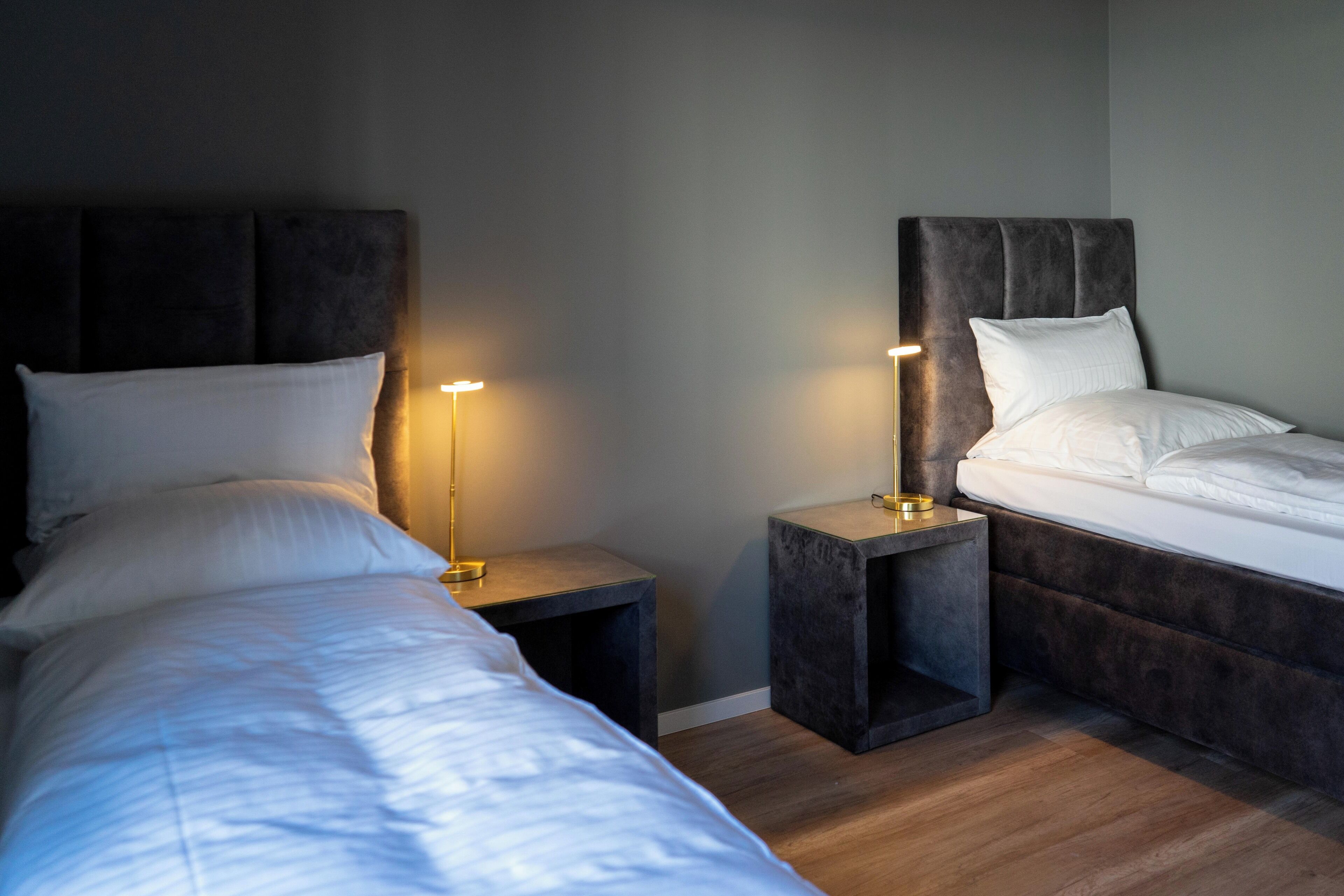 A bedroom with two beds, nightstands, and bedside lamps.