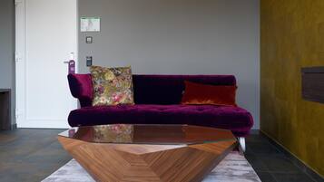 Un moderno salón con un sofá de terciopelo morado, una mesa de centro de cristal y un detalle decorativo de madera.